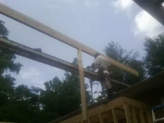 Carpenter setting a ridge beam over a new addition frame — Ice Dam Removal by Roofing Brothers in Tewksbury