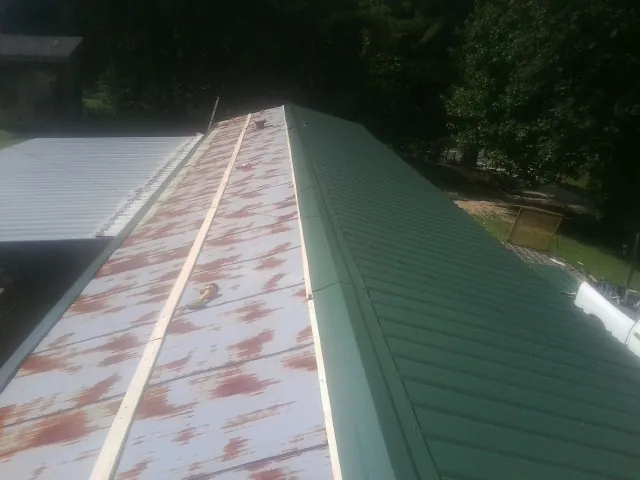 Old rusted panels beside newly installed green metal roofing — Wind Damage Roof Repair by Roofing Brothers in Tewksbury