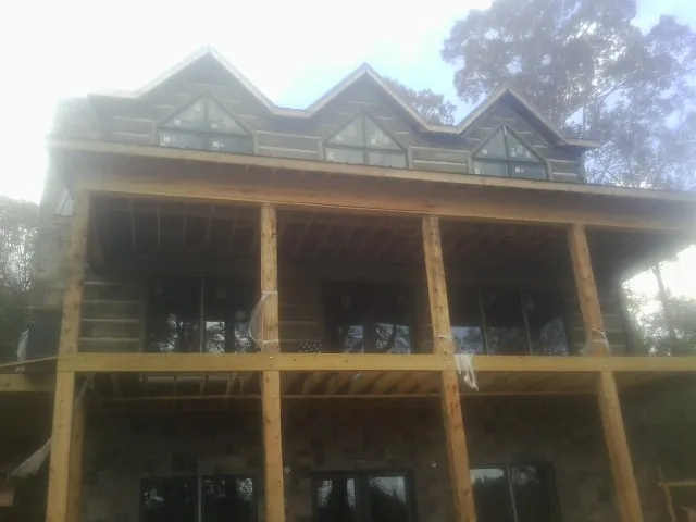Dormers and porch framing on a large log home under construction — Roof Coating work by our crew in Tewksbury