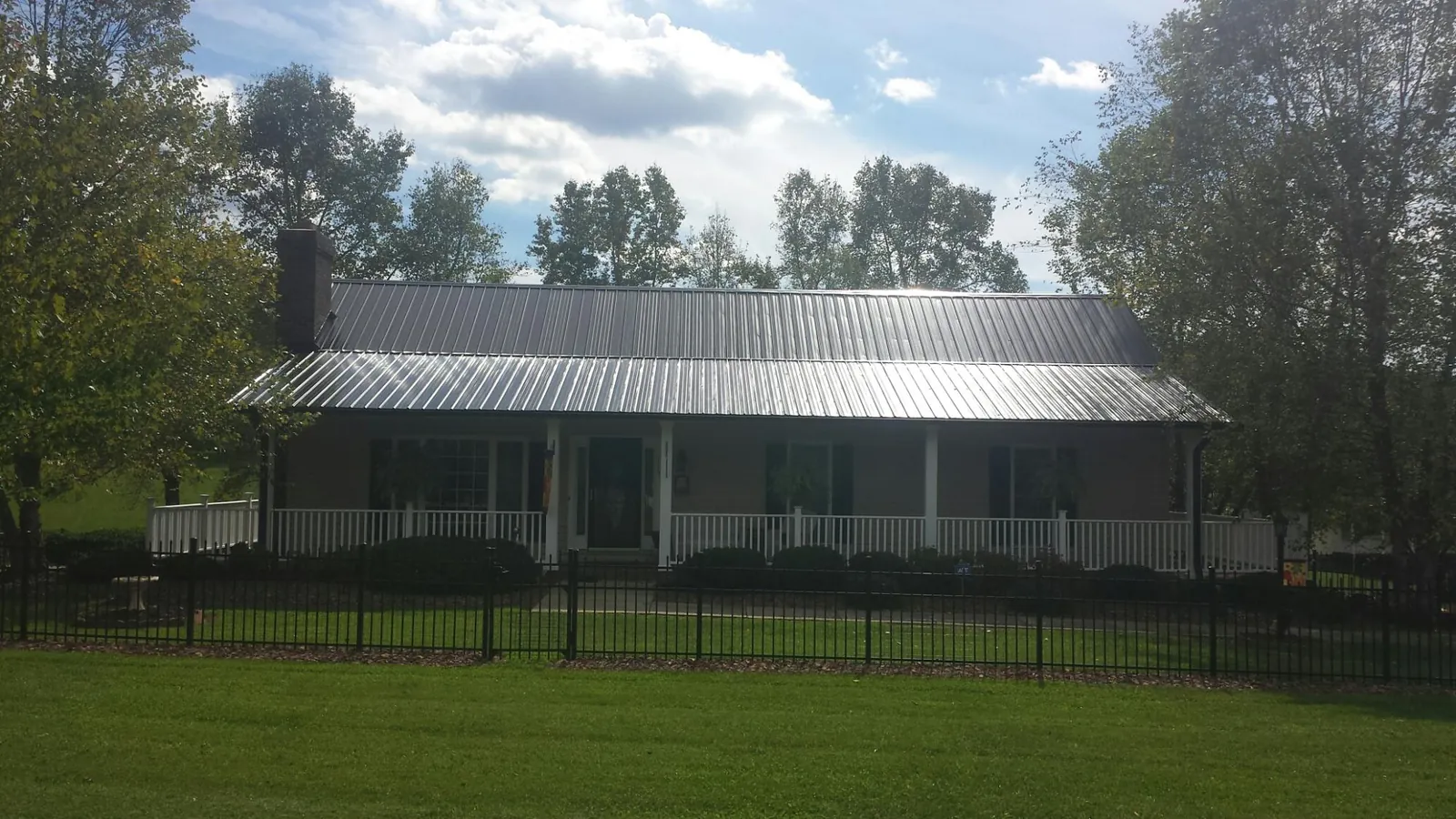 Gray metal roof on a brick ranch with a full width front porch — Gutter Guard Installation work by our crew in Tewksbury
