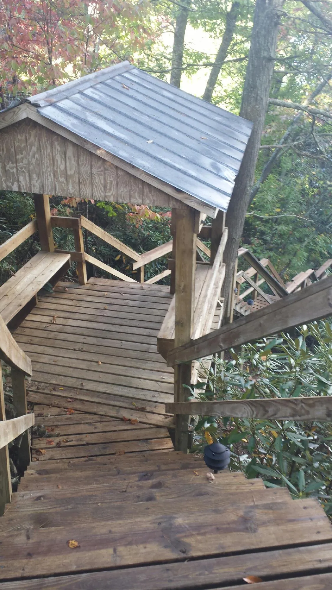 Metal roofed shelter over wooden steps on a wooded walkway — Skylight Repair & Installation work by our crew in Tewksbury