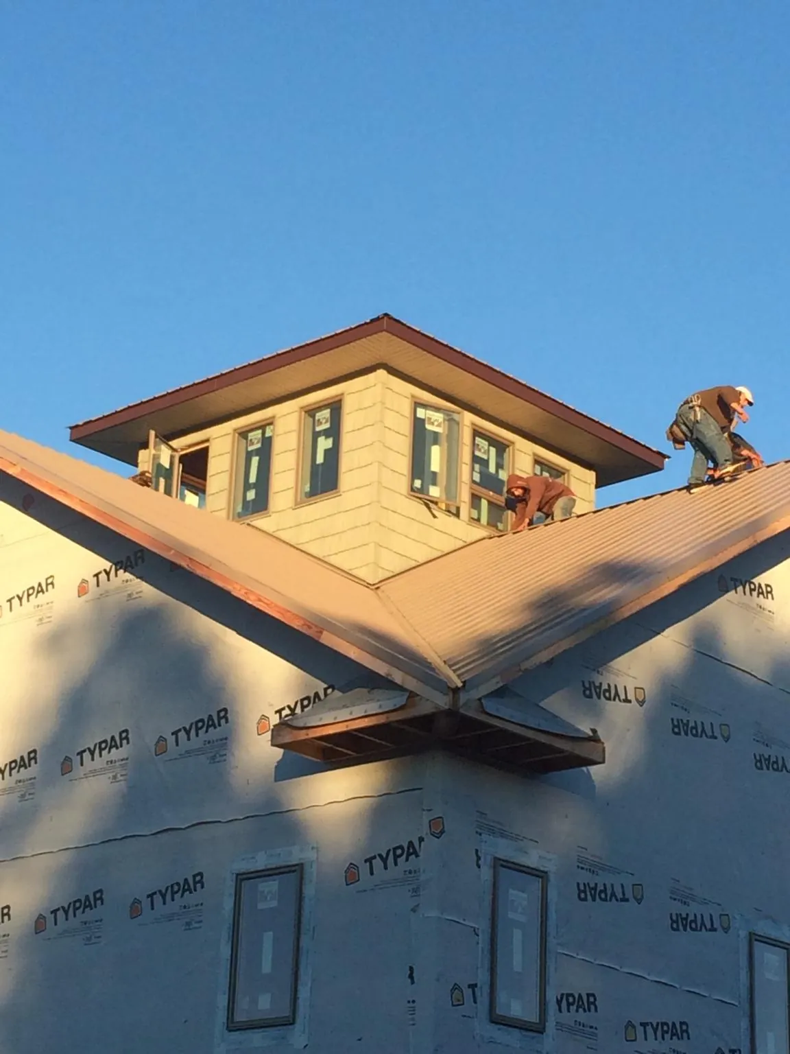 Roofers working around a rooftop cupola on a new metal roof at sunset — Roof Waterproofing in Tewksbury by Roofing Brothers